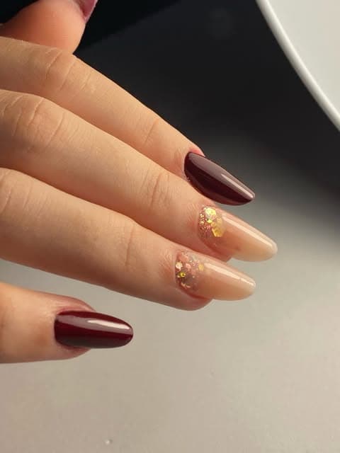 Unghie bordeaux con dettagli oro